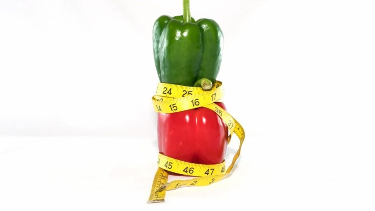 a red bell pepper wrapped in a measuring tape
