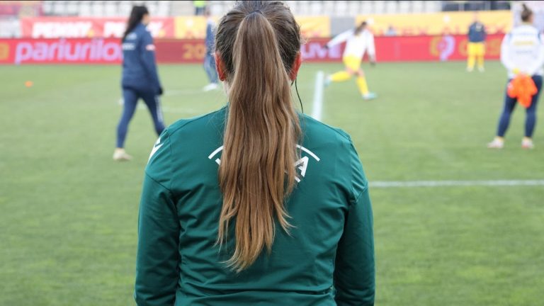 A woman watches a soccer game.